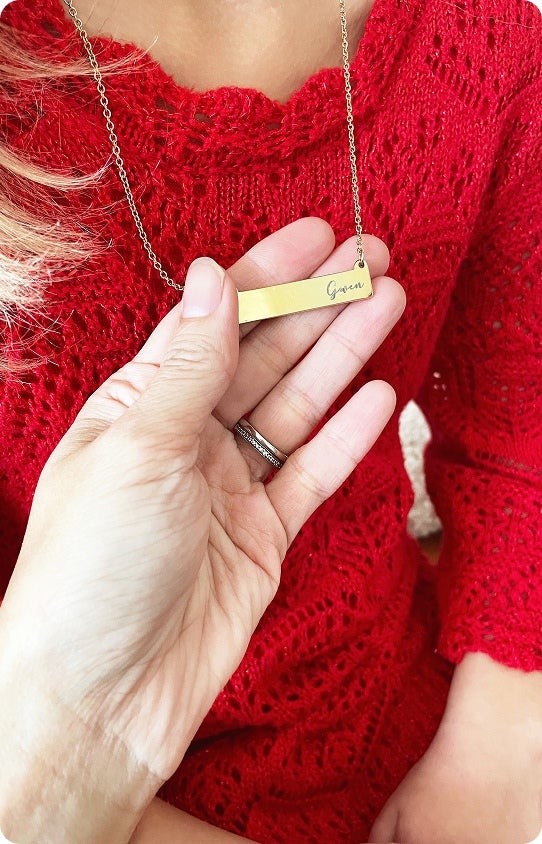 A woman holding an engraved Christmas jewelry item