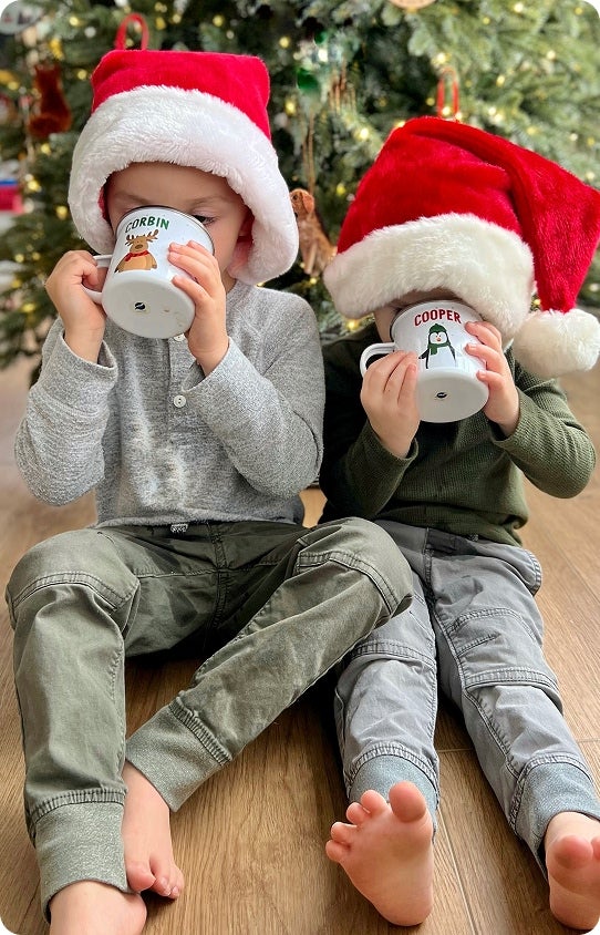 Two children drinking out of Christmas mugs with their names personalized on them