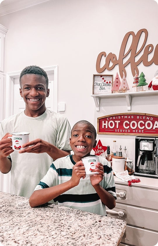Two children smiling and holding their personalized Christmas mugs